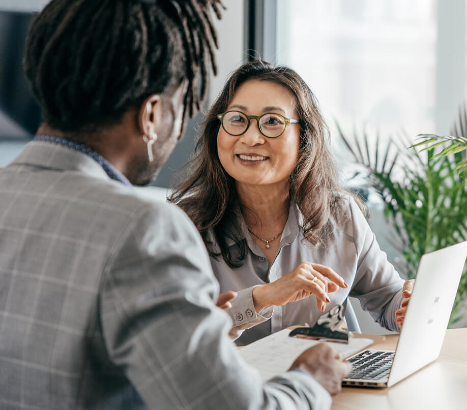 A woman smiling at a man. They are gesturing at a document.