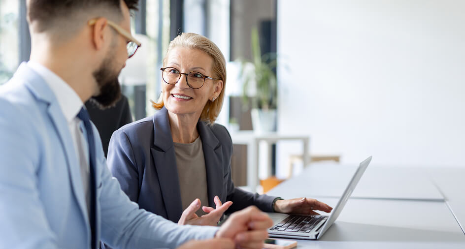 A woman smiling and gesturing. She is looking at a man turned away from camera.